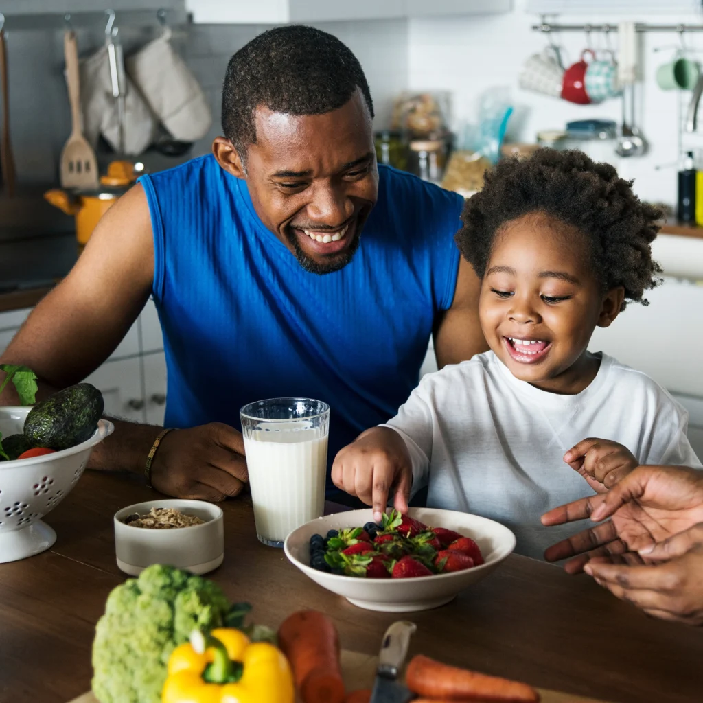 Father and child eating fruit at a kitchen table